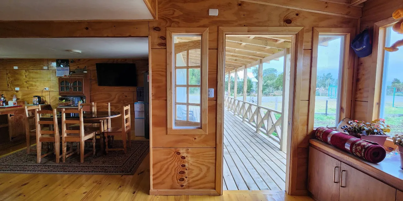 Interior de una cabaña, mostrando la sala de estar y la cocina equipada.